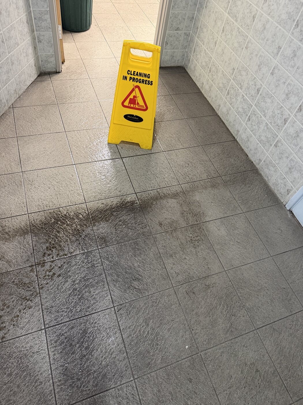 Freshly cleaned bathroom tiled floor with safety sign